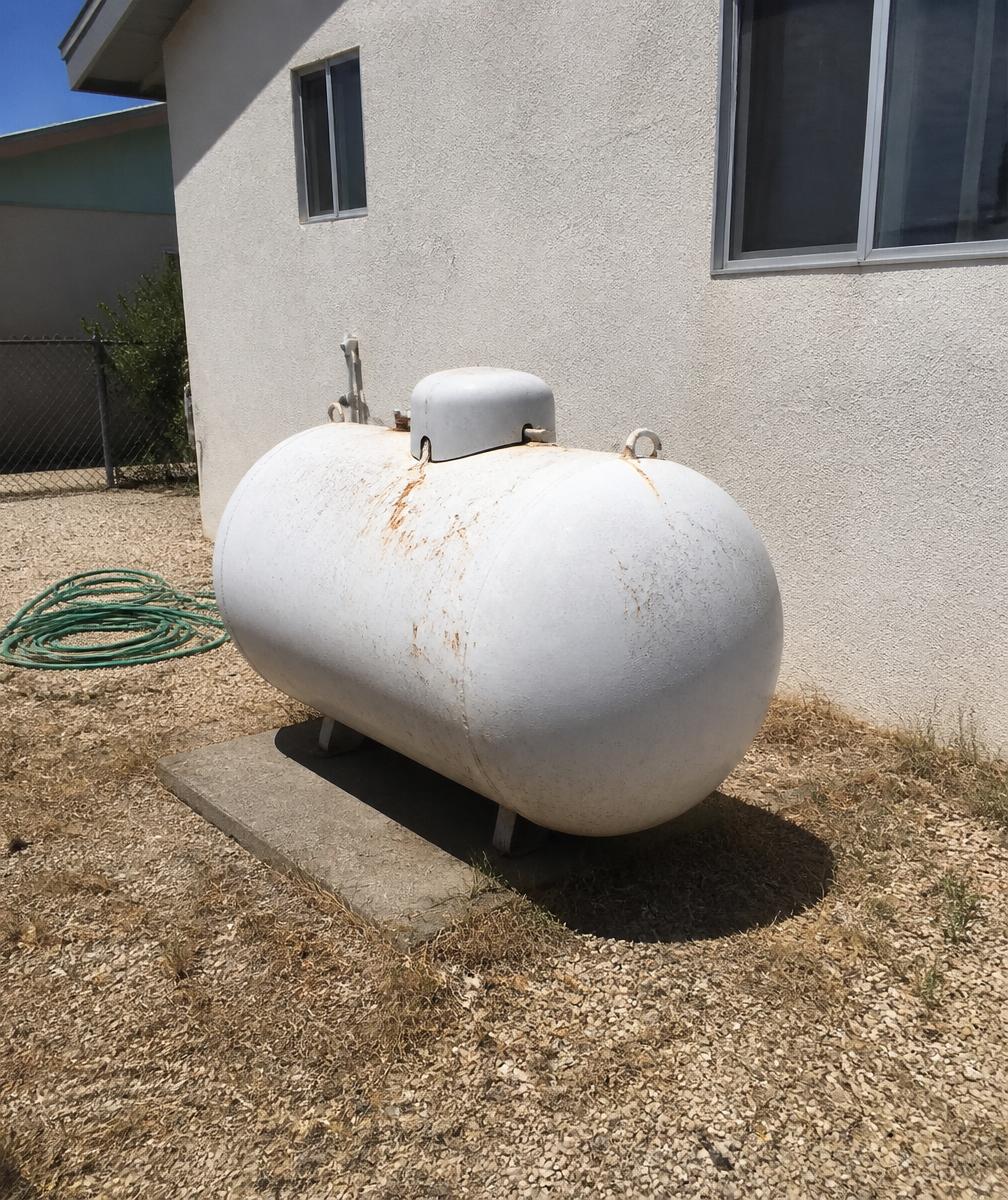 Residential propane tank on a concrete pad beside a stucco home
