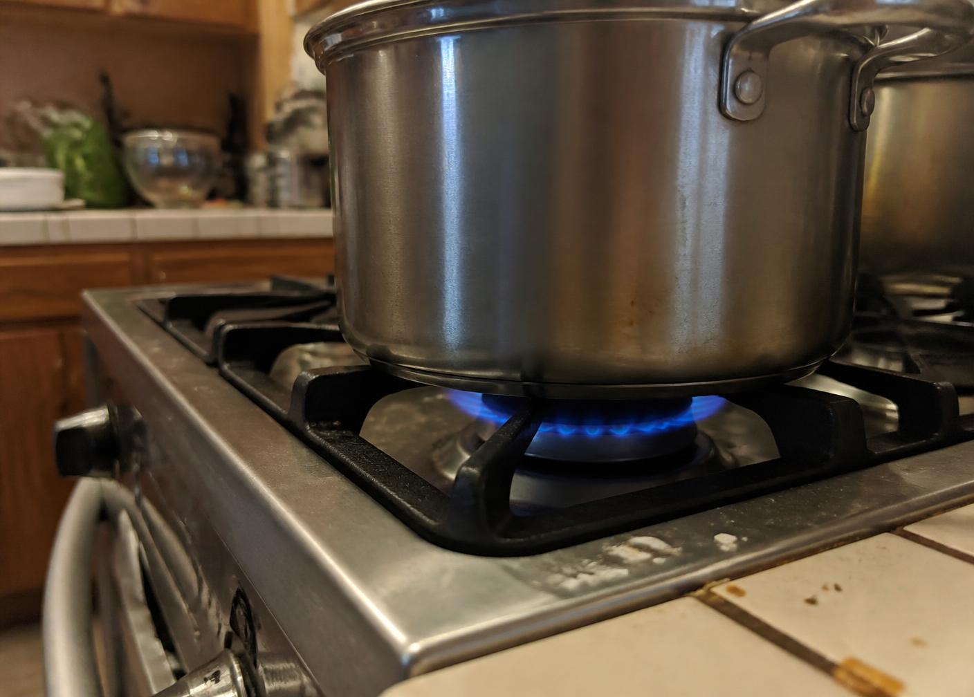Propane burner lit under a pot on a home kitchen range